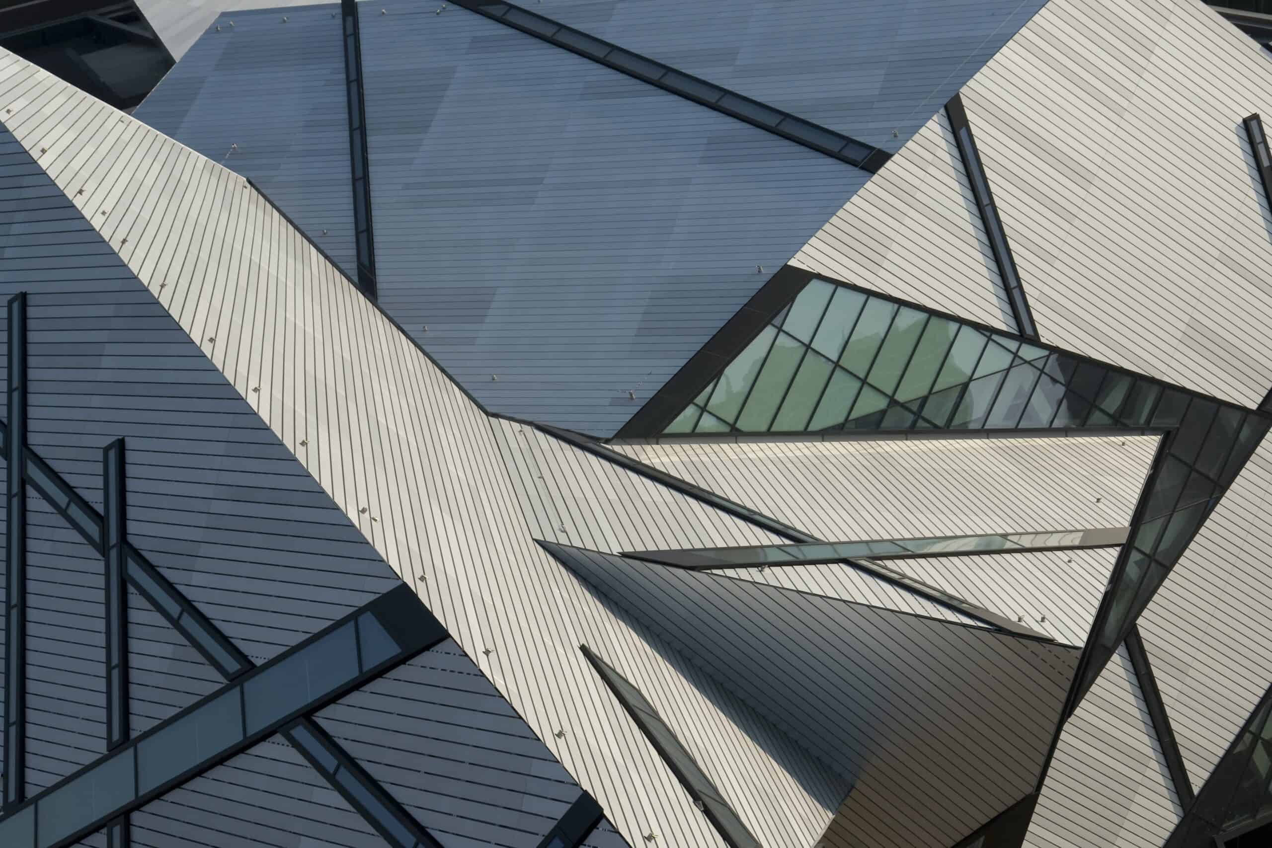 Close-up view of a modern building facade with intersecting metal and glass geometric shapes and angular lines.